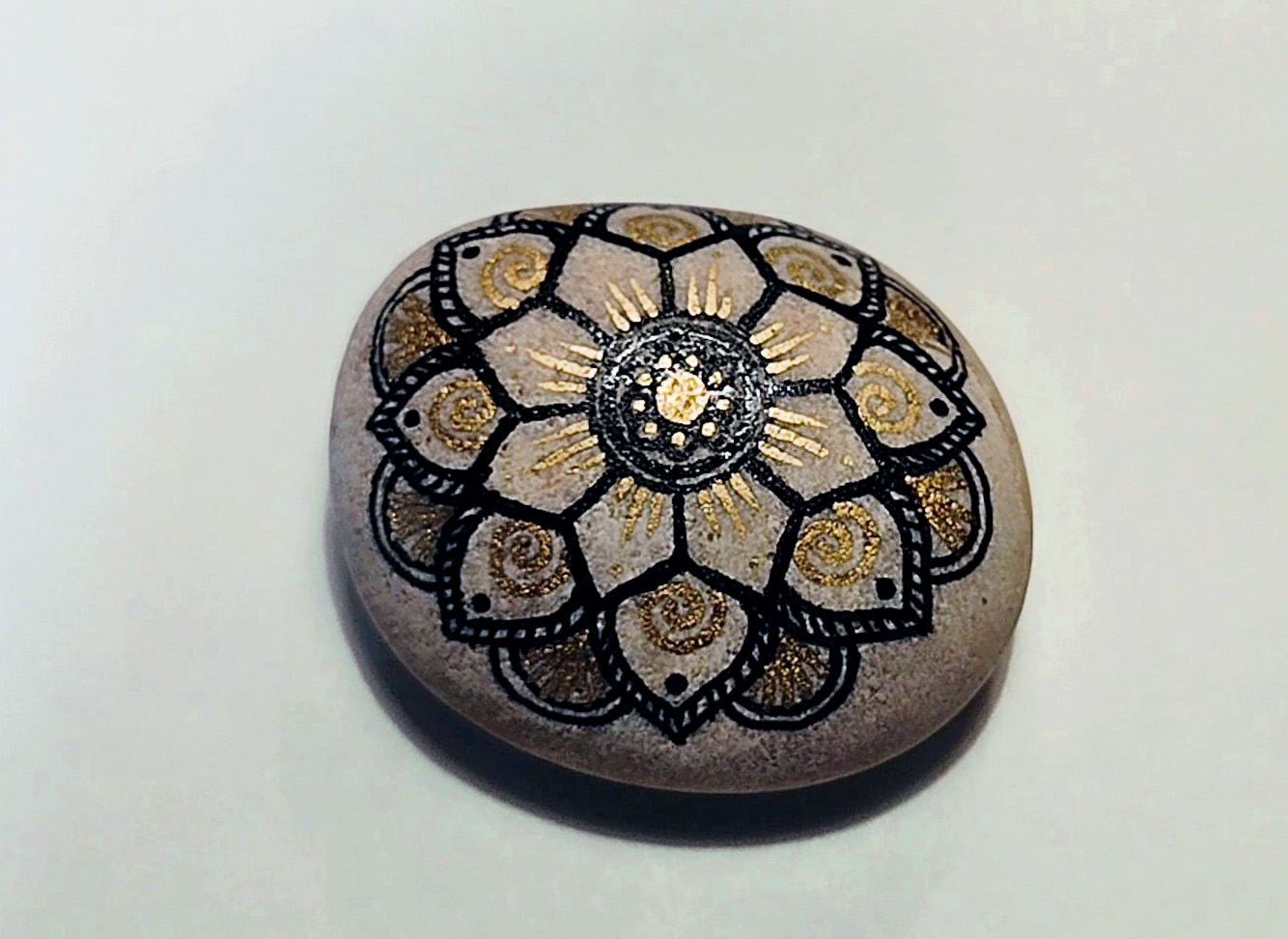 Finished memorial rock painted with black and gold floral mandala design