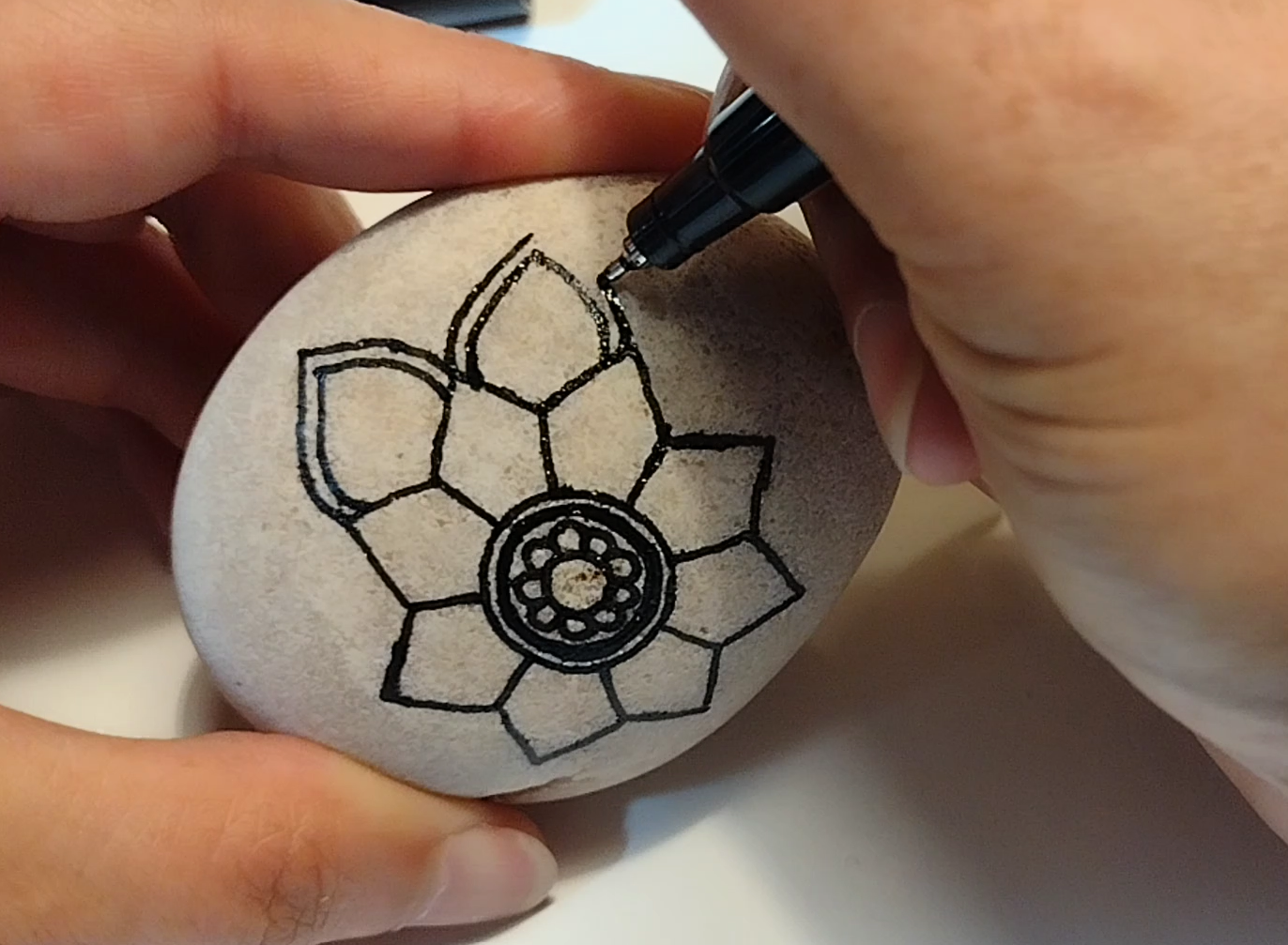 Becky painting a floral mandala design on Angelo Locatelli's memorial rock